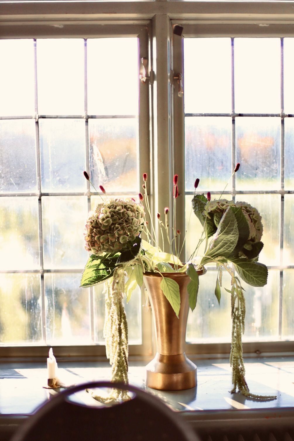 Blomsterarrangemang i mässingsvas i slottsfönstret