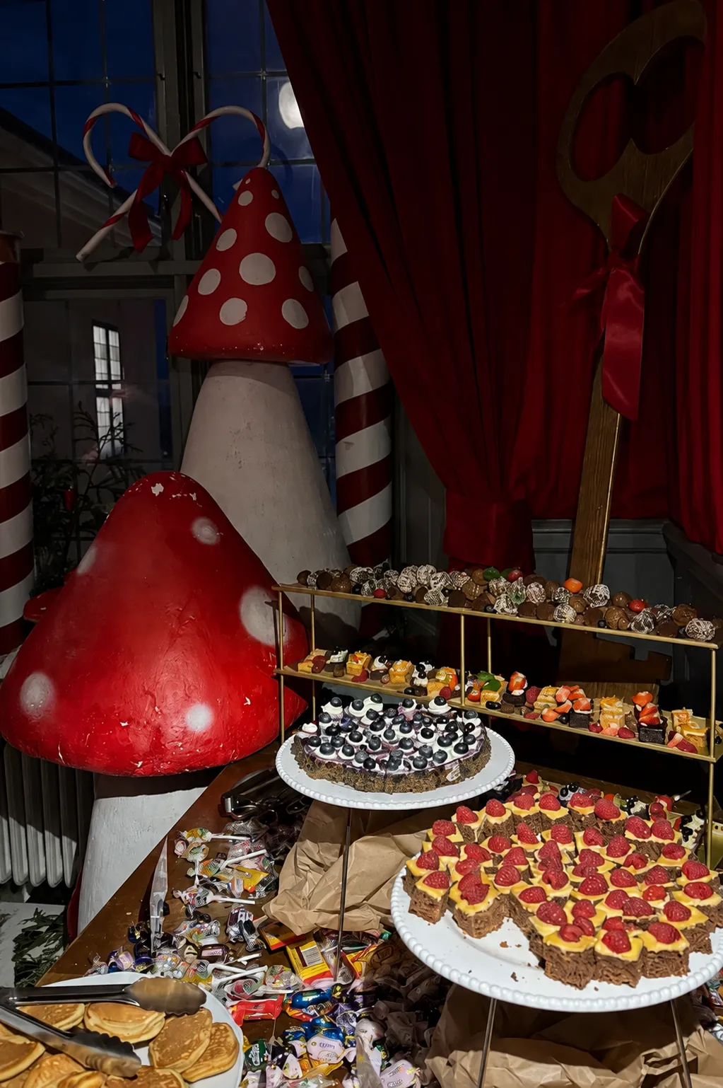 Julig dessertbuffé med bärtårtor, chokladpraliner och godis bland röda flugsvampar och polkagrisstolpar