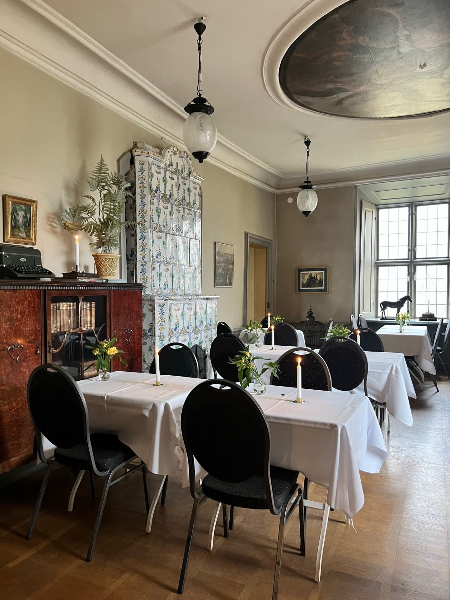 Mötesrum med blommig kakelugn och dukade bord