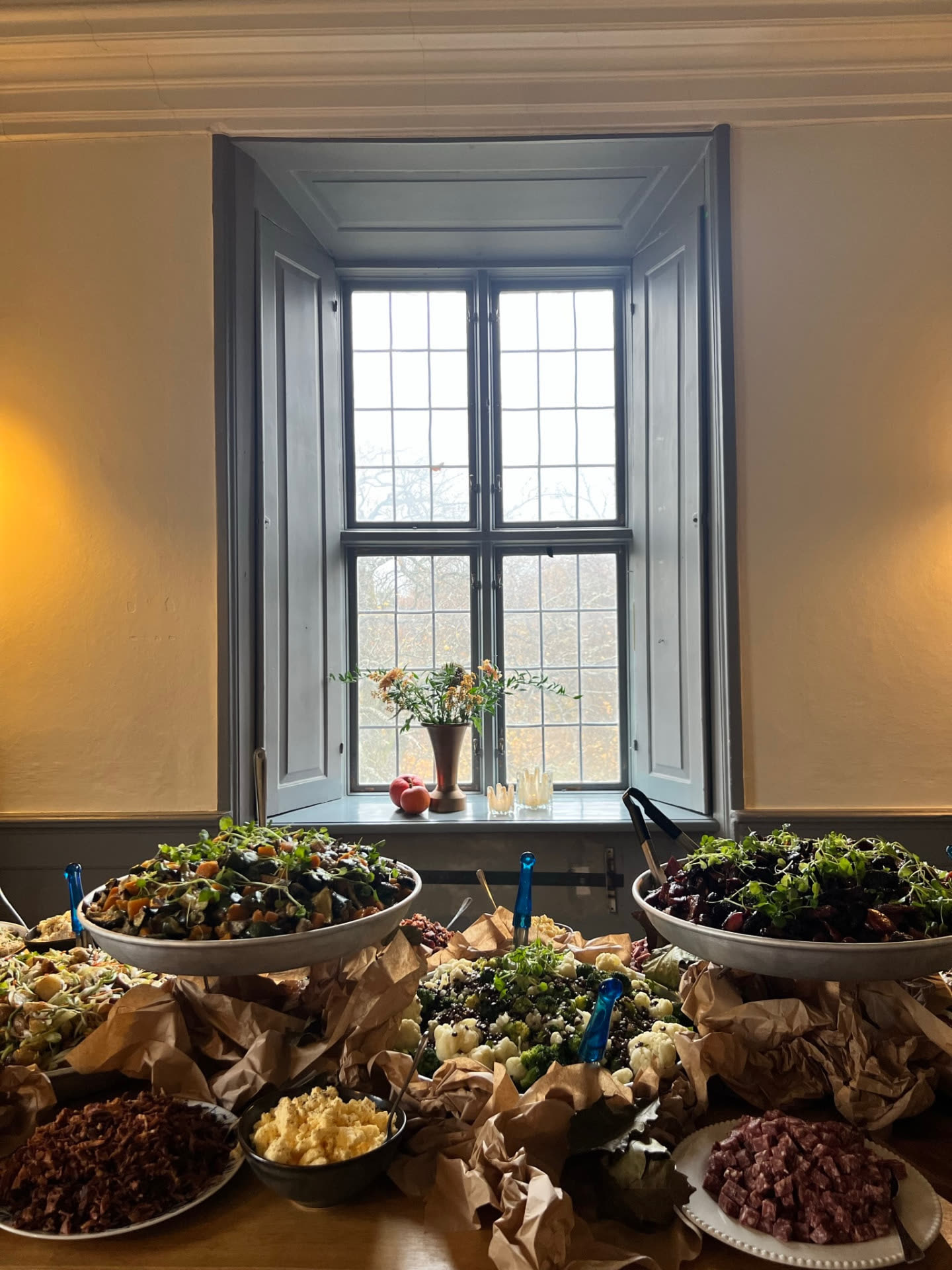 Buffébord med gröna sallader och chark framför slottsfönstret