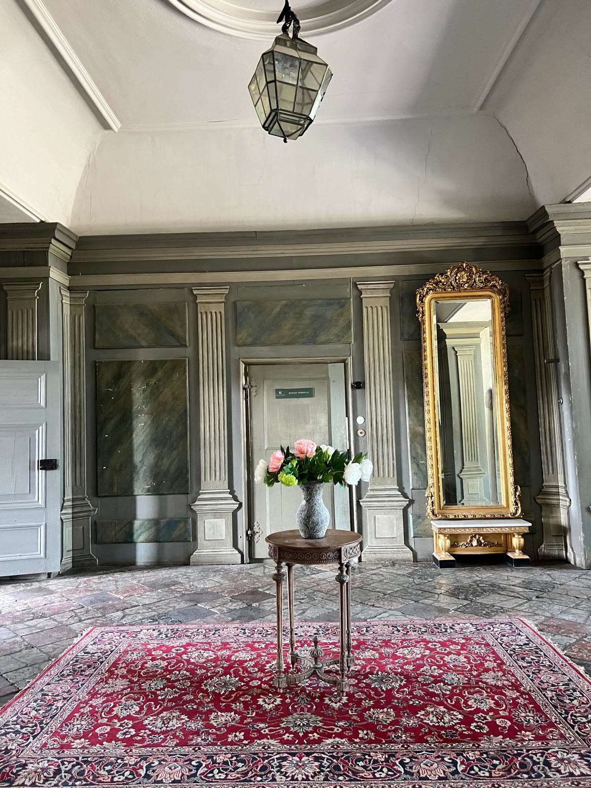 Entréhallen med förgylld spegel, marmorerade väggfält och blommor