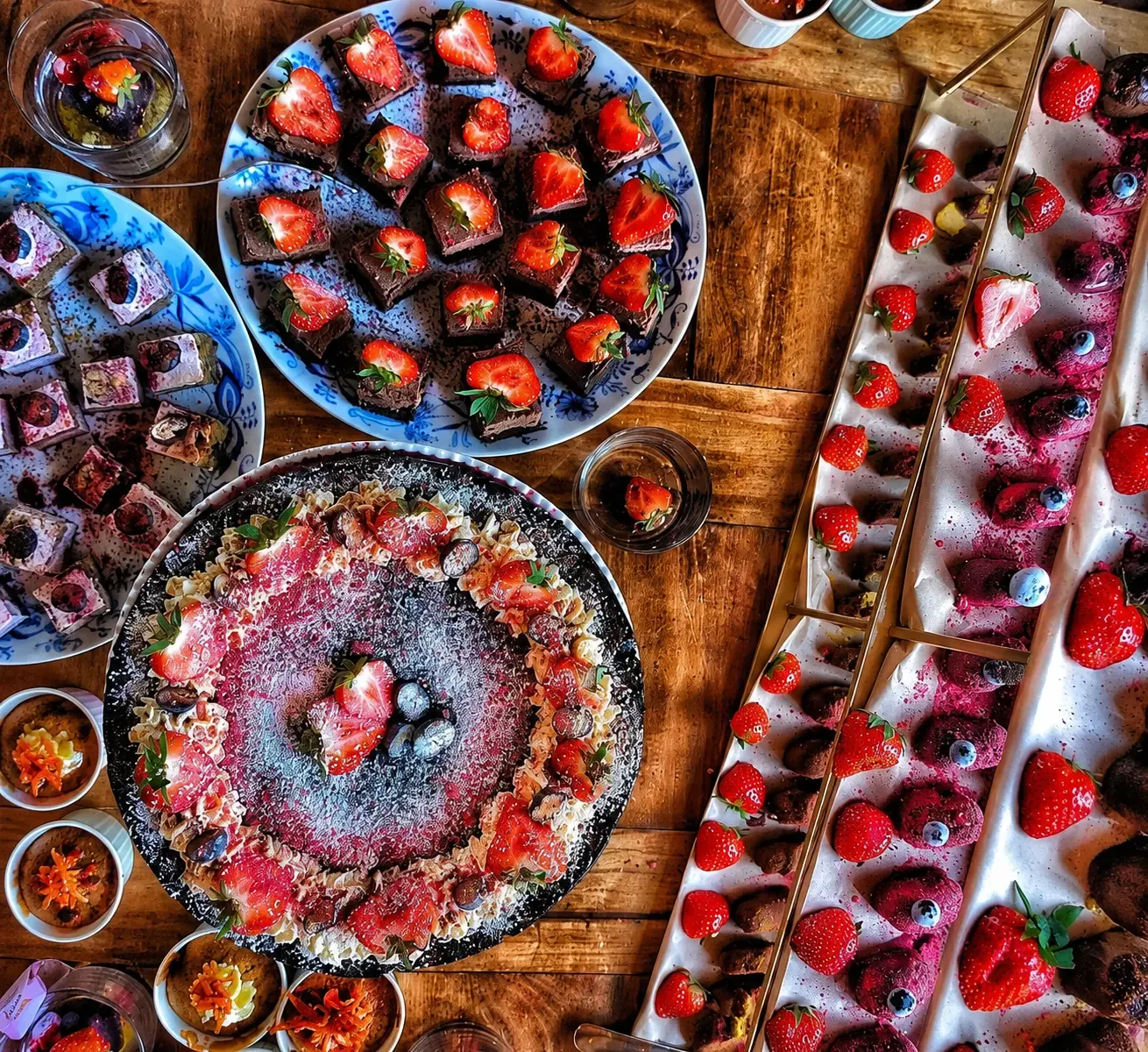 Dessertbuffé ovanifrån med chokladrutor, bär och små mousser