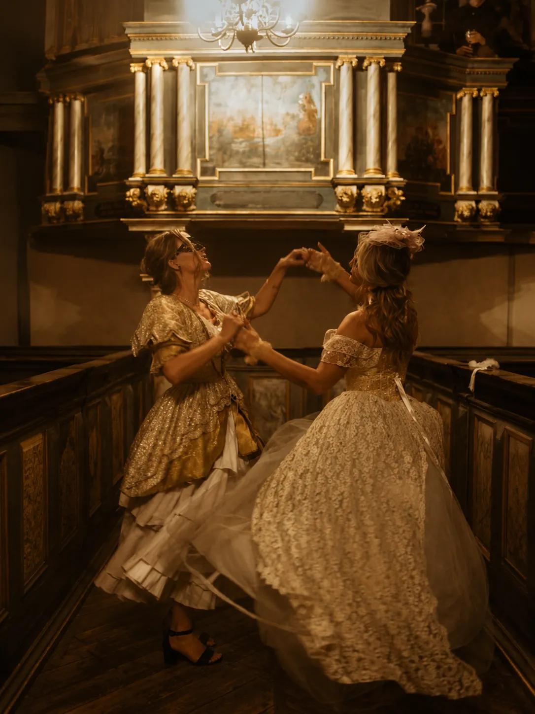 Två gäster i historiska dräkter dansar i slottskyrkans gyllene ljus
