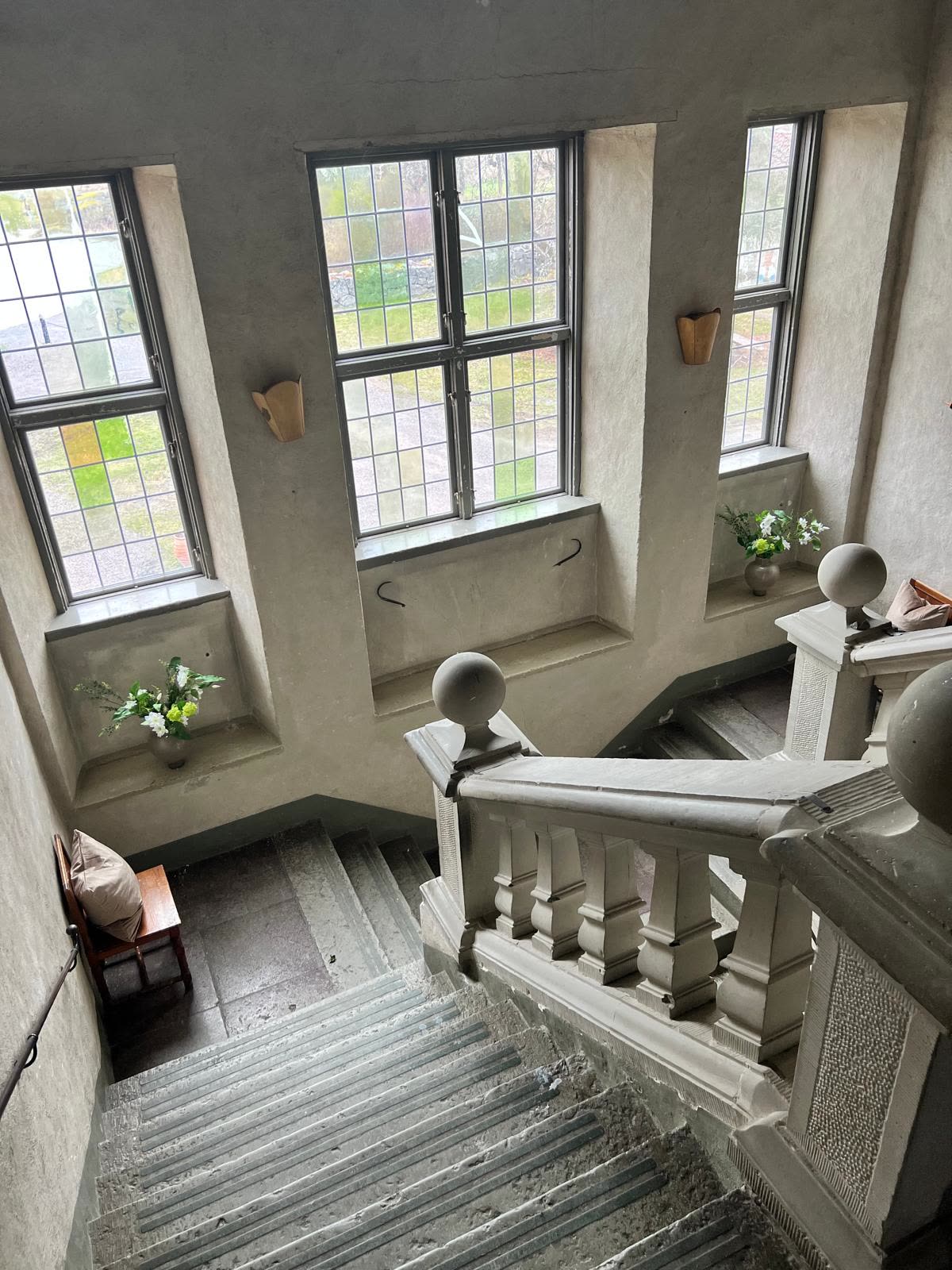 Vy nedför trapphuset med tre blyspröjsade fönster